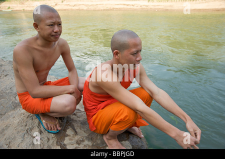 Zwei buddhistische Mönche sitzen auf einem Felsen im Fluss Nam Khan vor dem Schlafengehen ein erfrischendes Bad im Fluss Stockfoto