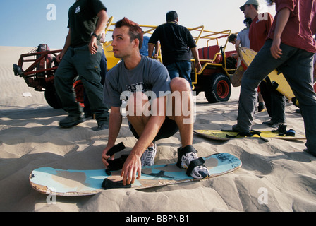 Junge europäische Reisende ausprobieren Sand boarding in den Sanddünen von Huacachina Peru Stockfoto