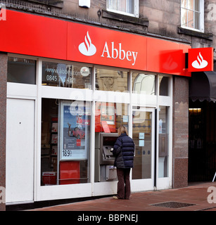 Eine Frau benutzt ein Geldautomat Cashpoint bei einer Filiale der Abtei Gebäude Gesellschaft Teil der Santander Gruppe Stockfoto