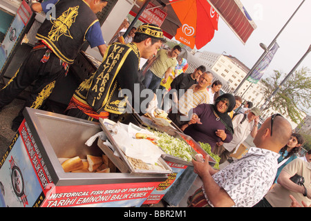 Istanbul Türkei türkische Frau kauft einen gebratenen Fisch Sandwich bekannt als ein Balik Ekmek von einem Straßenhändler in Eminönü Stockfoto