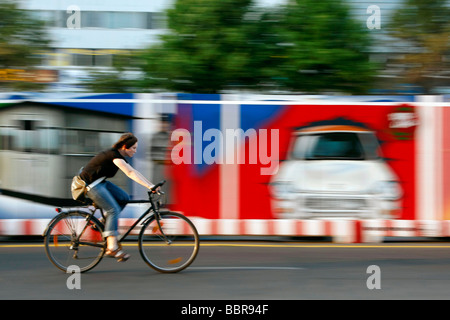 RADFAHRER VOR EINEM VERSCHALTEN ZAUN ZUR VERANSCHAULICHUNG DES KALTEN KRIEGES, CHECKPOINT CHARLIE UND EIN TRABANT, ALEXANDERPLATZ, BERLIN, DEUTSCHLAND Stockfoto