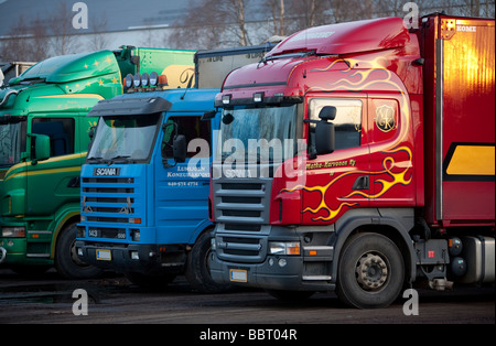 Lineup von rot, blau und grün geparkten LKW, Finnland Stockfoto