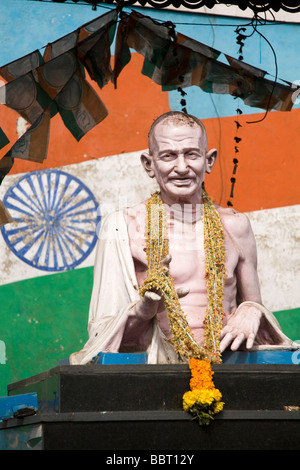 Die bekränzten Statue von Mahatma Gandhi steht vor der indischen Flagge. Stockfoto