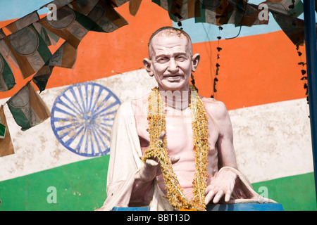 Die bekränzten Statue von Mahatma Gandhi steht vor der indischen Flagge. Stockfoto