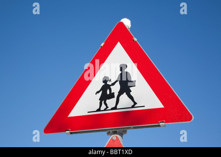 Dreieckige Warnzeichen für Kinder beim Überqueren der Straße vor blauem Himmelshintergrund. UK-Großbritannien-Europa Stockfoto