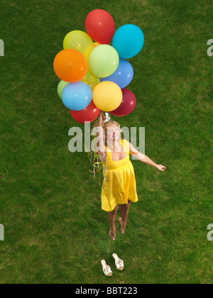 Junge glückliche Frau von Grund auf bunte Luftballons fliegen Stockfoto