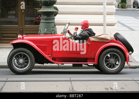 Roter Vintage Aero 1000 aus dem Jahr 1933 oder 1934 parkte auf einer Stadtstraße mit einem Fahrer in roter Kappe und schwarzer Jacke hinter dem Steuer Stockfoto