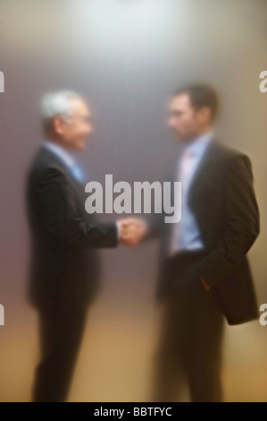 Männer Händeschütteln hinter Matt Leinwand Stockfoto