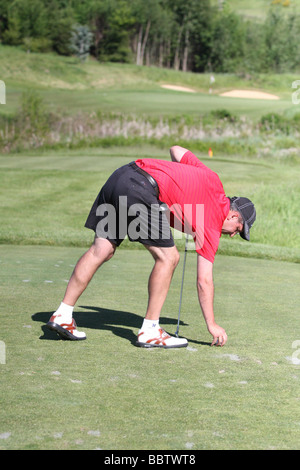 Ein erwachsenen männlichen Golfer Abschläge seiner Golf-Ball zwischen den Abschlag Markern auf der Teebox ein Par 3, bevor man seinen Abschlag. Stockfoto