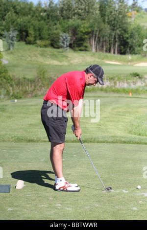 Ein männlichen Golfer durchläuft seine Schaukel Vorbereitung Routine vor der Kollision mit seinem Abschlag mit einem Eisen von der Teebox ein Par 3. Stockfoto