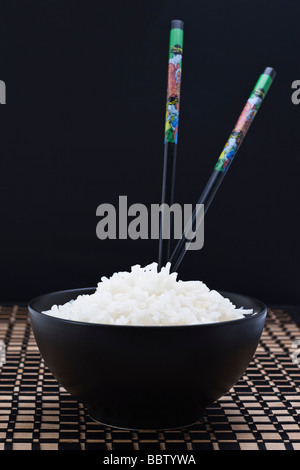 Gekochten Reis in schwarze Schale mit zwei Stäbchen Stockfoto