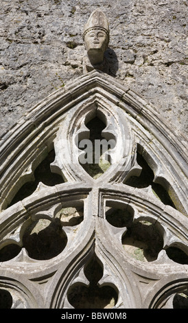 Geschnitzten Kopf des irischen Bischofs über eine aufwendige gotische Fenster. Stockfoto
