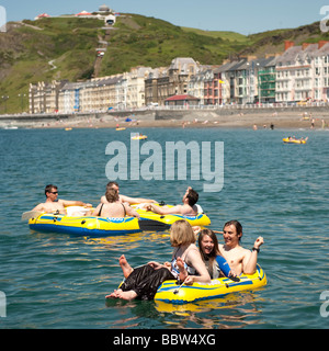 Aberystwyth Universitätsstudenten am Meer in aufblasbaren Dinghys an einem heißen Sommertag am Ende des Sommers Begriff Gurte UK Stockfoto