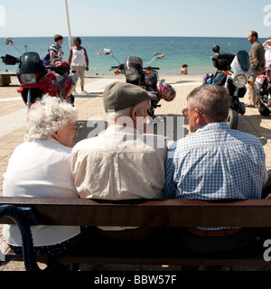 Drei ältere Menschen sitzen auf einem Meer Bank sprechen und im Chat an einem Sommernachmittag Aberystwyth Wales UK Stockfoto