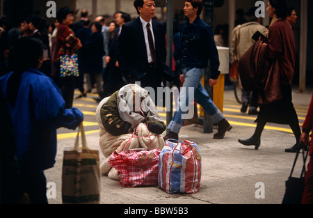 Passanten ignorieren mittellose Stadtstreicherin in Hong Kong Tsim Sha Tsui auf der Kowloon Seite Straße Stockfoto