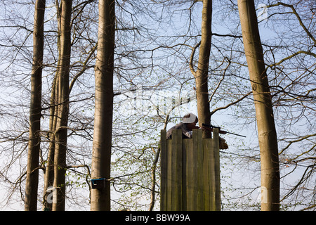 Ein elf Jahre alten Jungen genießt Zielübungen mit einem Teleskop.22 Luftgewehr von oben eines hausgemachten Turms in Familie Wald Stockfoto