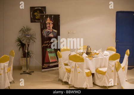 Ein Banner-Porträt des sudanesischen Präsidenten Omar Hassan Ahmad al Bashir in der Nähe von gedeckten Tischen in Womens Projekt showroom Stockfoto