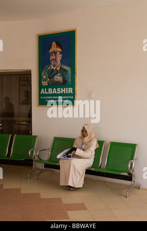 Darfurs Dame wartet unter imposanten Porträt ihrer sudanesischen Präsidenten Omar Hassan Ahmad al-Baschir Al Fashir Flughafen Stockfoto