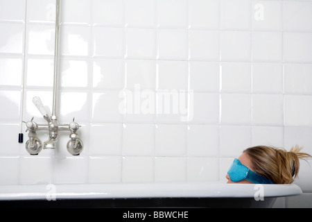 junge Frau in der Badewanne tragen eine Augenmaske Stockfoto