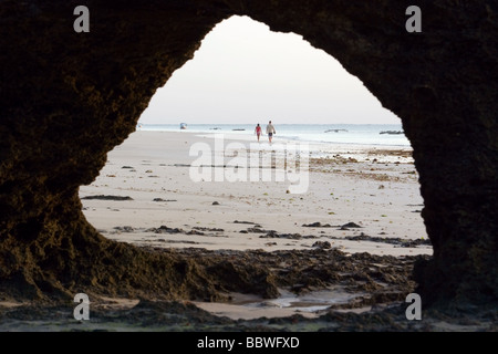 Paare, die am Strand eingerahmt von Höhle - Diani Beach - in der Nähe von Mombasa, Kenia Stockfoto