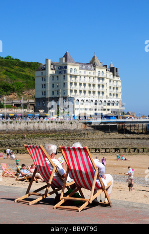 Ältere Menschen sitzen in Liegestühlen auf der Promenade, Llandudno, North Wales, UK Stockfoto