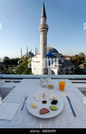 Frühstückstisch mit Teller auf der Dachterrasse eines kleinen Hotels in Sultanahmet, Blick auf Firuz Aga-Moschee und die blaue Moschee, Istan Stockfoto