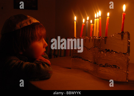 Ein kleiner Junge starrt auf das Hanukkah Menorah auf der achten Nacht brennen Stockfoto