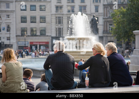 Menschen entspannen Sie rund um den Brunnen am Trafalgar Square an einem späten Sommernachmittag, London, England. Stockfoto