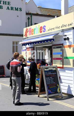 Teenager Schuljungen Line-up Burger mittags während ihren Tagesausflug zum Lyme Regis Fossil Festival Dorset kaufen Stockfoto