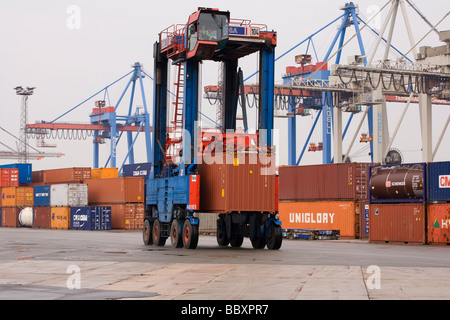 Ein Straddle Carrier LKW bewegt sich ISO-Container um den Container terminal gestapelt und verarbeitet werden. Stockfoto