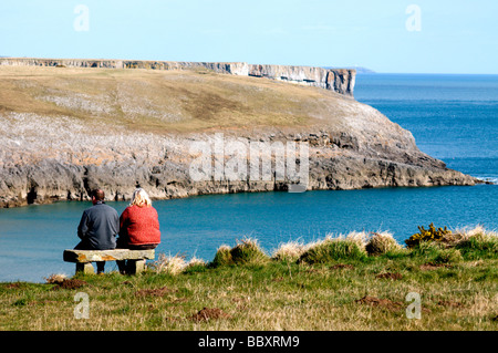 Paar auf Bank mit Blick auf das Meer und die Klippen von Bosherston, Pembrokshire sitzen. Stockfoto