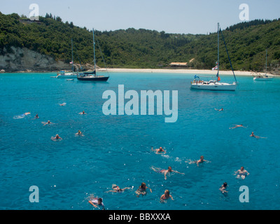 Yachten vor der Insel Anti Paxos Griechenland mit angetäut Viele Menschen schwimmen im kristallklaren türkisfarbenen Meer Stockfoto