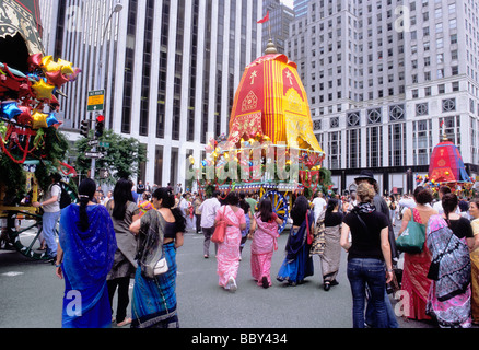 New York City Hare Krishna Prozession auf der Fifth Avenue. Frauen in Saris folgen den bunten Festwagen der Parade. Zuschauer beobachten auf der Straße. Stockfoto