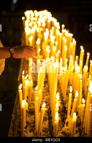 Mann Beleuchtung votive Kerze in der Kirche Stockfoto