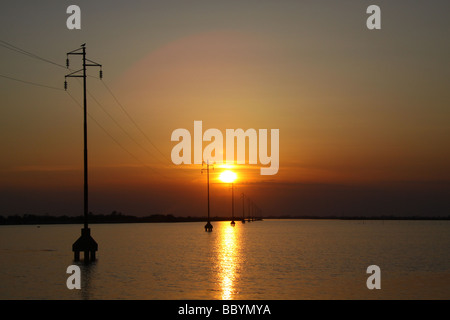 Sonnenuntergang und Silhouette macht Kabel Pylonen, Versorgung Insel Albarella, Italien Stockfoto