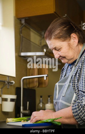 Frauenbeschneidung, 67 Jahre alt, Frühlingszwiebeln in der Küche Stockfoto