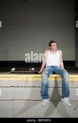 Skateboarder sitzt auf einer Laderampe, erschöpft Stockfoto