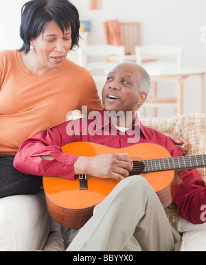 Afrikanischer Mann spielt Gitarre für Frau Stockfoto