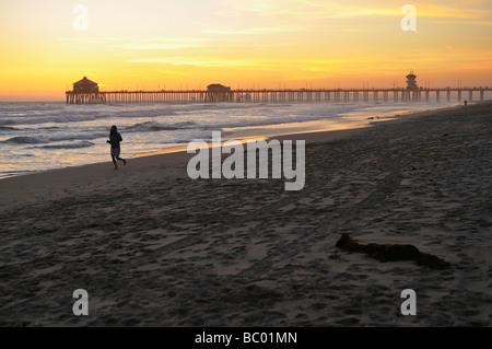 Eine Frau, Jogging am Strand bei Sonnenuntergang, Huntington Beach CA Stockfoto