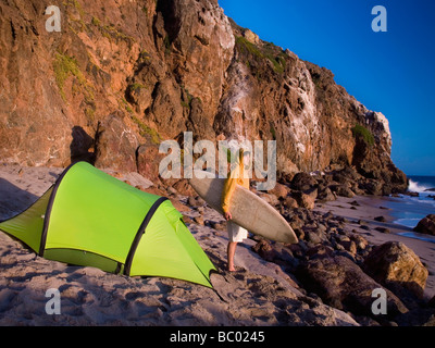 Ein junger Mann am Strand warten auf Surf camping. Stockfoto