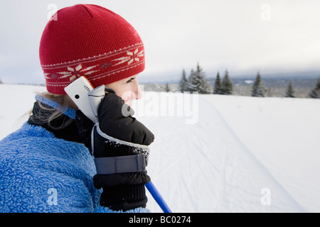 Eine junge Frau auf einem Handy beim Langlaufen im Gespräch. Stockfoto