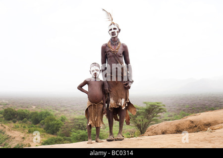 Eine Großmutter steht mit ihrem Enkel, gekleidet in traditioneller Kleidung mit Blick auf das Omo-Tal im Süden Äthiopiens. Stockfoto