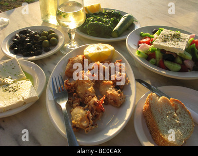 Griechische Küche Crete Griechenland Feta Kalamari Oliven Salat und Vleeta Stamnagathi Wildgemüse mit Weißwein Stockfoto