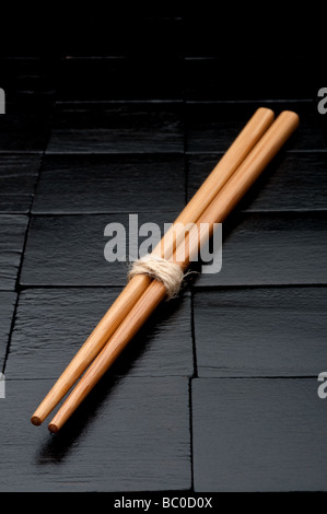 vertikale Nahaufnahme von Stäbchen auf einem schwarzen Hintergrund aus Holz Stockfoto
