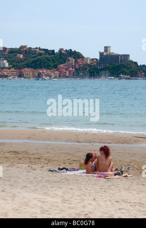 Ein paar liegen am Strand von San Terenzo, ligurischen Küste in den Golf der Poeten in der Nähe von La Spezia mit Lerici in der Ferne Stockfoto