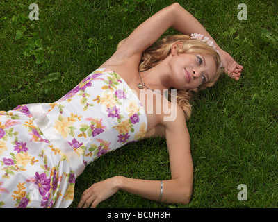 Junge Frau im Sommerkleid liegen auf dem grünen Rasen Stockfoto