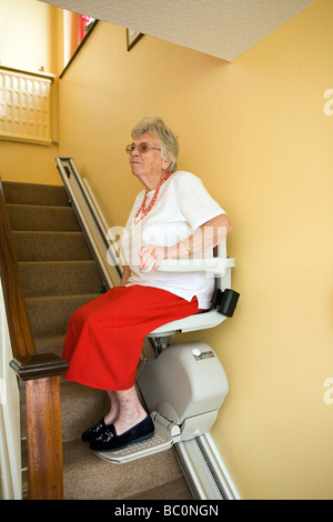 Eine alte Dame nutzt eine Sessellift in ihrem Haus die Treppen hoch und runter bewegen Stockfoto