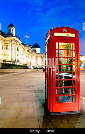 Rote Telefonzellen in der Nacht neben dem Trafalgar Square, London, mit der Nationalgalerie im Hintergrund auf der linken Seite. Stockfoto