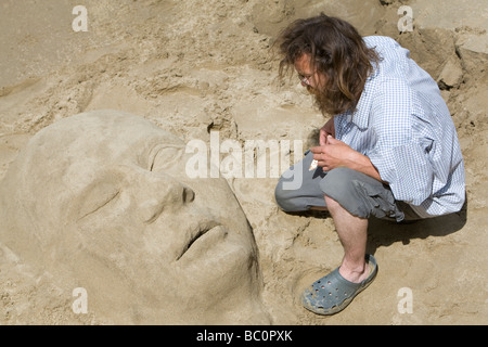 Ein Künstler arbeitet auf eine Sandskulptur an einem Strand am Südufer des Flusses Themse London UK Stockfoto