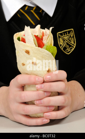 Schulmädchen halten einen Chicken Salat wickeln mit gepflegten Nägeln Stockfoto